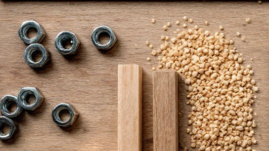 Loose nuts, timber offcuts and granules arranged on a wooden workbench